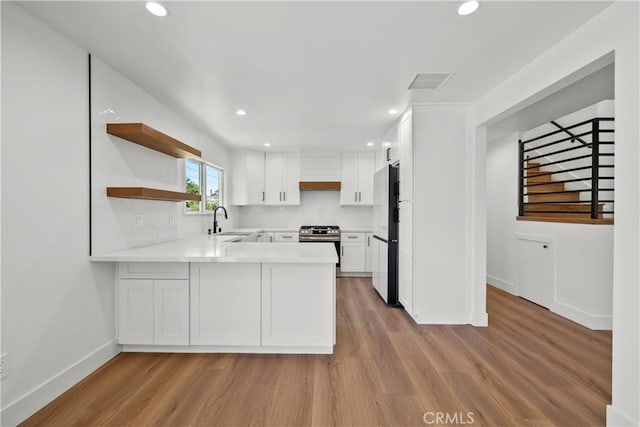 19548 Cedarcreek St, Canyon Country, CA 91351 - kitchen featuring freestanding refrigerator, a peninsula, open shelves, light countertops, and light wood-type flooring
