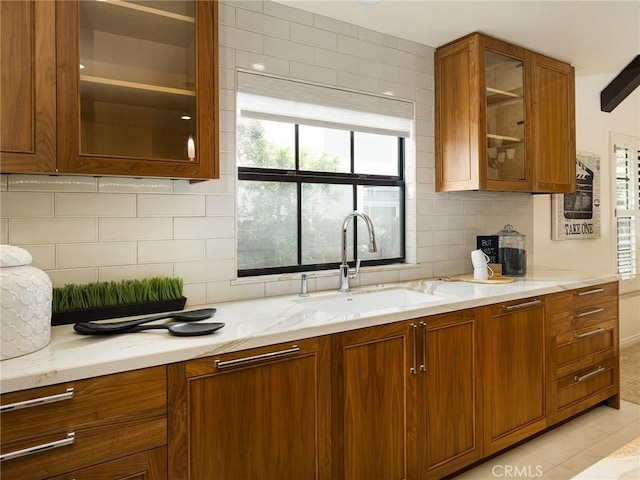 502 Washington St, El Segundo, CA 90245 - kitchen with brown cabinetry, glass insert cabinets, backsplash, and light stone counters