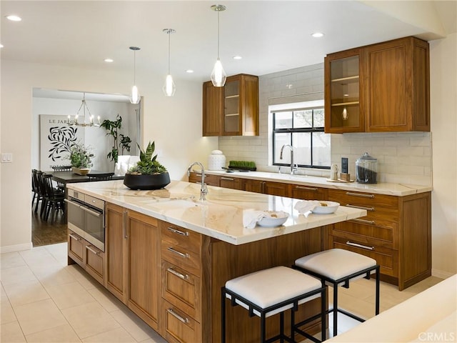 502 Washington St, El Segundo, CA 90245 - kitchen featuring tasteful backsplash, brown cabinets, glass insert cabinets, light stone counters, and recessed lighting