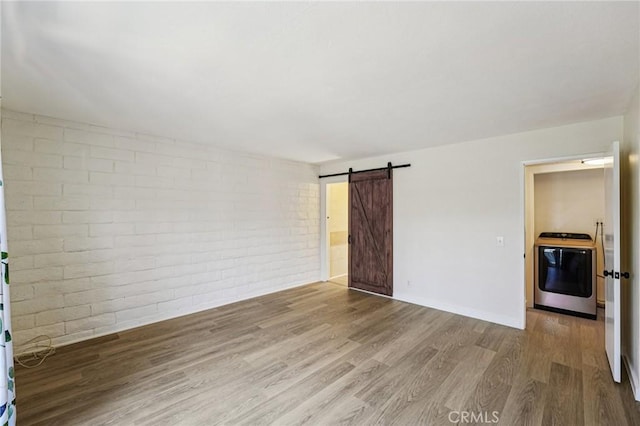 750 Via Los Santos, San Dimas, CA 91773 - spare room featuring washer / dryer, wood finished floors, brick wall, and a barn door