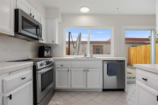 2811 Via Topacio, Carlsbad, CA 92010 - kitchen with stainless steel appliances, tile counters, white cabinetry, light tile patterned floors, and a peninsula