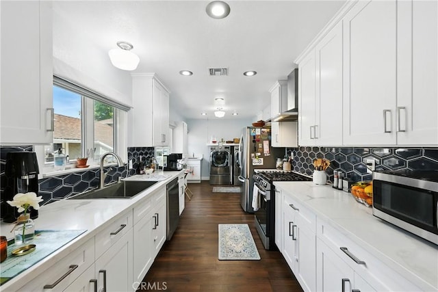 7604 Forest Ave, Whittier, CA 90602 - kitchen featuring appliances with stainless steel finishes, wall chimney range hood, washing machine and dryer, white cabinets, and recessed lighting
