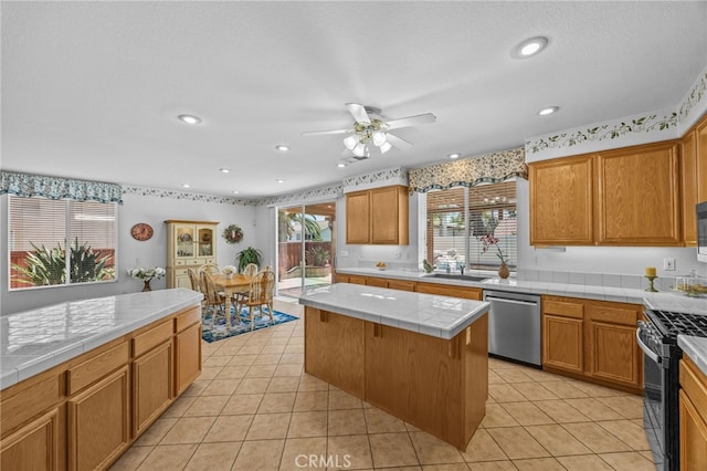 20865 Westbury Rd, Riverside, CA 92508 - kitchen with appliances with stainless steel finishes, tile countertops, a ceiling fan, a kitchen island, and light tile patterned flooring