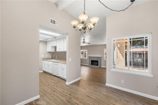 4633 Dowel Ave, Palmdale, CA 93552 - kitchen with white dishwasher, beamed ceiling, a fireplace with raised hearth, white cabinets, and a chandelier