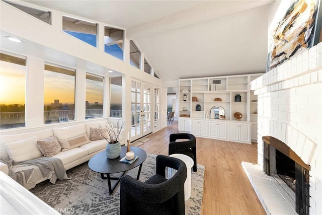 11 Montpellier Unit 22, Newport Beach, CA 92660 - living area featuring french doors, beam ceiling, high vaulted ceiling, light wood-type flooring, and a brick fireplace