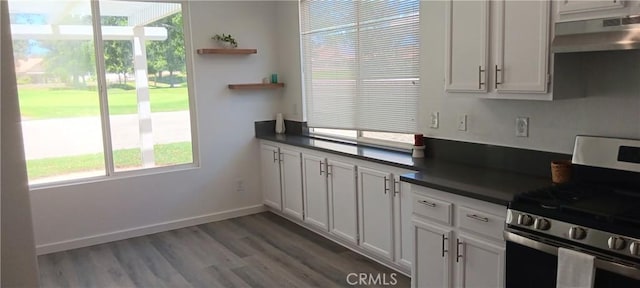 720 Big Spring Dr, Banning, CA 92220 - kitchen with stainless steel gas stove, dark countertops, open shelves, under cabinet range hood, and light wood-type flooring