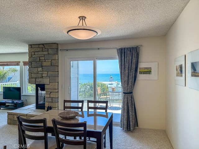 557 Lucerne St, Cayucos, CA 93430 - carpeted dining area featuring a textured ceiling, a stone fireplace, healthy amount of natural light, and a water view