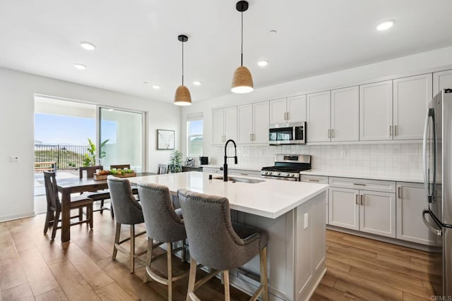 35188 Orchard Trl, Fallbrook, CA 92028 - kitchen featuring stainless steel appliances, light wood-style floors, tasteful backsplash, a kitchen island with sink, and light countertops