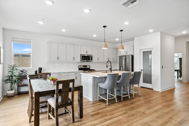 35188 Orchard Trl, Fallbrook, CA 92028 - kitchen with stainless steel appliances, decorative backsplash, a center island with sink, light countertops, and light wood finished floors