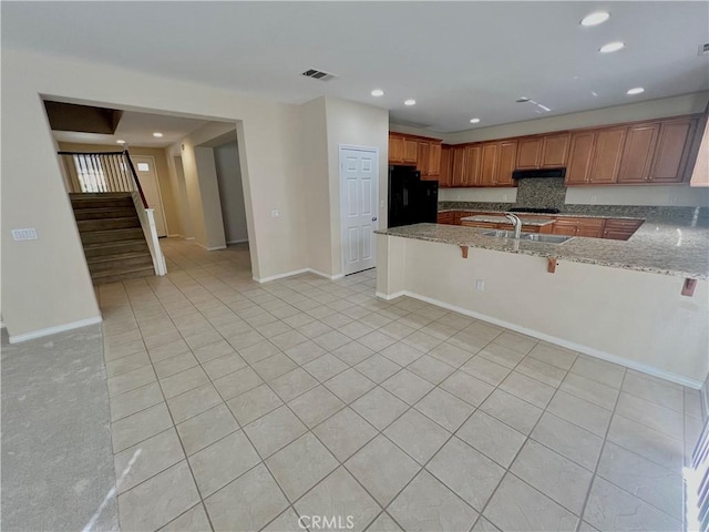 3642 Neola Way, Lancaster, CA 93536 - kitchen featuring black appliances, a peninsula, light stone countertops, under cabinet range hood, and a kitchen breakfast bar