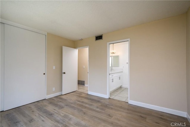 1881 Mitchell Ave Unit 8, Tustin, CA 92780 - unfurnished bedroom with light wood-type flooring, a closet, connected bathroom, and a textured ceiling