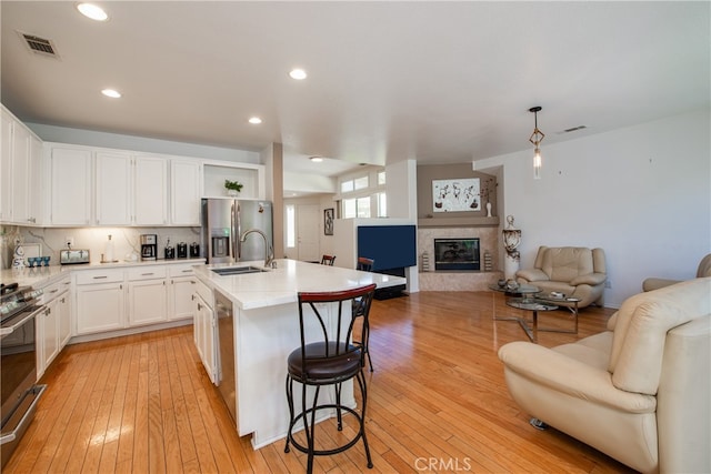 29427 Bentcreek Ct, Menifee, CA 92584 - kitchen with open floor plan, stainless steel appliances, white cabinets, light countertops, and light wood-style flooring