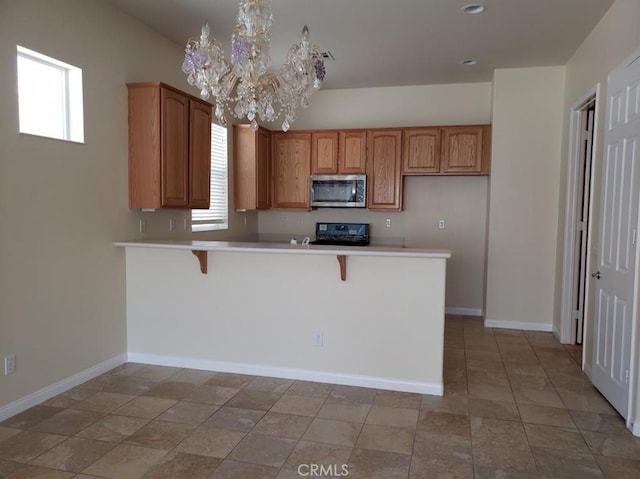 11142 Avonlea Rd, Apple Valley, CA 92308 - kitchen featuring stainless steel microwave, stove, a chandelier, a peninsula, and a breakfast bar area