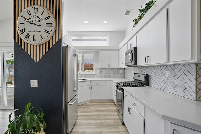 28591 Corvus Way, Menifee, CA 92586 - kitchen with stainless steel appliances, light countertops, white cabinetry, light wood-type flooring, and decorative backsplash