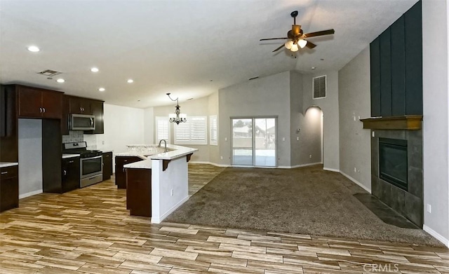 12745 Autumn Leaves Ave, Victorville, CA 92395 - kitchen featuring appliances with stainless steel finishes, wood finished floors, a fireplace, a ceiling fan, and recessed lighting