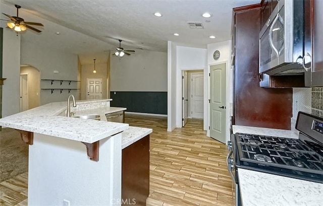12745 Autumn Leaves Ave, Victorville, CA 92395 - kitchen featuring stainless steel appliances, ceiling fan, light wood-style floors, vaulted ceiling, and a breakfast bar area