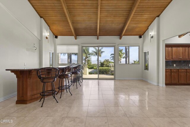590 Alosta Dr, Camarillo, CA 93010 - kitchen featuring a wooden ceiling with exposed beams, a kitchen bar, light tile patterned flooring, brown cabinets, and high vaulted ceiling