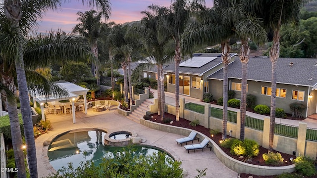 590 Alosta Dr, Camarillo, CA 93010 - back of property with roof mounted solar panels, a fenced backyard, a pool with connected hot tub, a patio area, and stucco siding