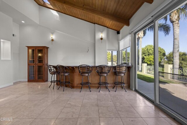 590 Alosta Dr, Camarillo, CA 93010 - kitchen with a wooden ceiling with exposed beams, high vaulted ceiling, a breakfast bar area, light tile patterned floors, and glass insert cabinets