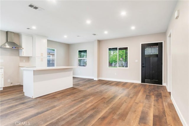 3067 Genevieve St, San Bernardino, CA 92405 - kitchen featuring wall chimney range hood, a center island, wood finished floors, white cabinets, and plenty of natural light