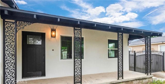 3067 Genevieve St, San Bernardino, CA 92405 - view of exterior entry with stucco siding, a porch, and a gate