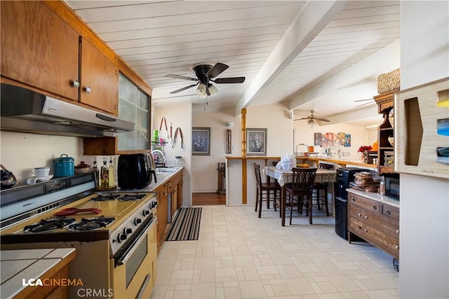 5 Dunlap, Bakersfield, CA 93309 - kitchen featuring white range with gas stovetop, under cabinet range hood, a ceiling fan, beamed ceiling, and brown cabinetry
