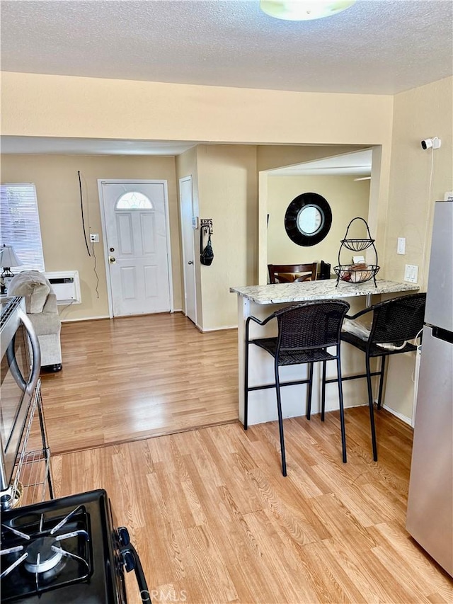 2616 N King St, Bakersfield, CA 93305 - foyer entrance featuring light wood-style flooring, a wall unit AC, and a textured ceiling
