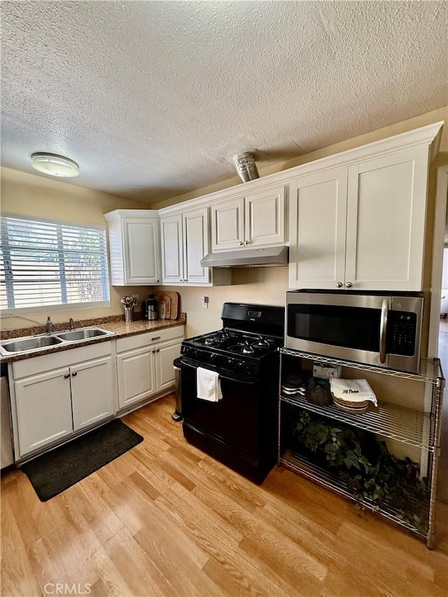 2616 N King St, Bakersfield, CA 93305 - kitchen with gas stove, stainless steel microwave, under cabinet range hood, white cabinets, and a textured ceiling