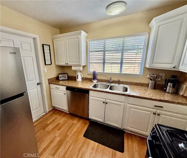 2616 N King St, Bakersfield, CA 93305 - kitchen with appliances with stainless steel finishes, light wood-style floors, white cabinetry, and a textured ceiling