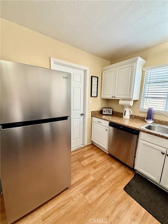 2616 N King St, Bakersfield, CA 93305 - kitchen with appliances with stainless steel finishes, white cabinets, light wood-style flooring, and a textured ceiling