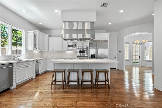 25471 Prado De Oro, Calabasas, CA 91302 - kitchen featuring built in appliances, ventilation hood, white cabinets, a chandelier, and decorative backsplash