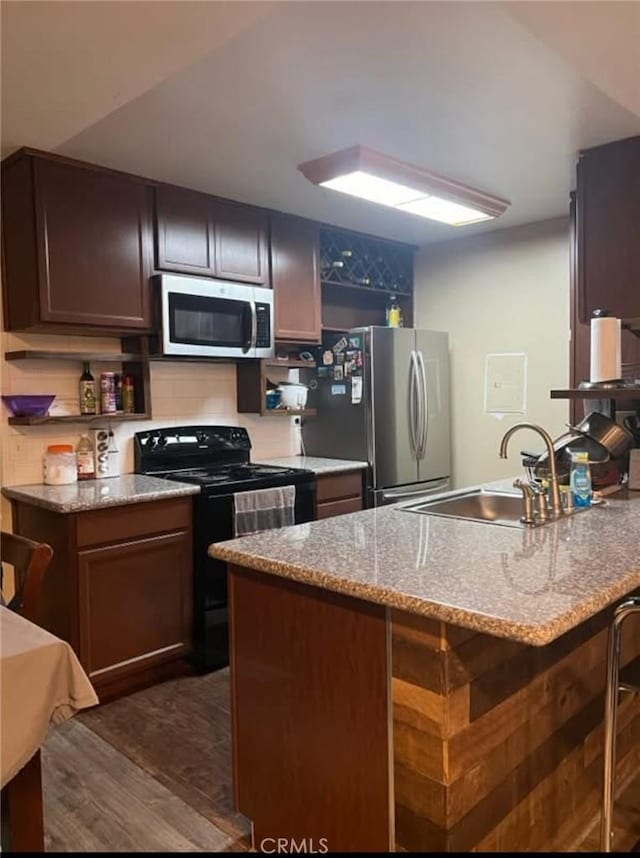23515 Lyons Ave Unit 277, Valencia, CA 91355 - kitchen with stainless steel appliances, dark wood-type flooring, light stone counters, a breakfast bar, and a peninsula