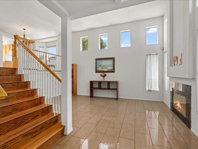 19025 Windridge Ln, Huntington Beach, CA 92646 - foyer featuring stairway, a glass covered fireplace, a high ceiling, and a chandelier