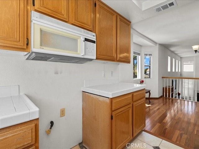 19025 Windridge Ln, Huntington Beach, CA 92646 - kitchen featuring white microwave, tile countertops, and brown cabinets