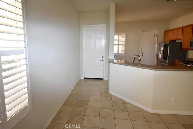 19485 Tor Hill Ln, Apple Valley, CA 92308 - kitchen with appliances with stainless steel finishes, light tile patterned flooring, and brown cabinetry