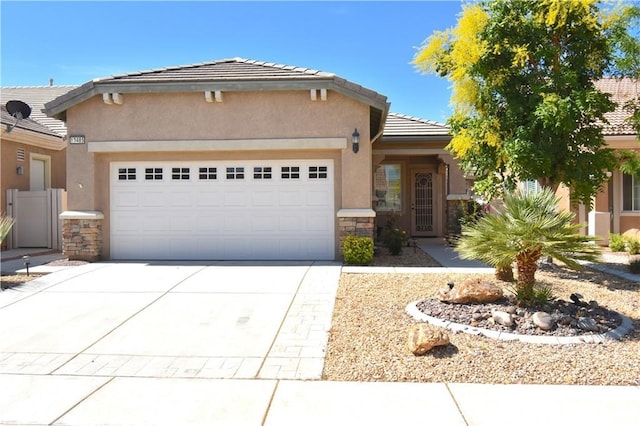 19485 Tor Hill Ln, Apple Valley, CA 92308 - view of front of property featuring stone siding, a garage, driveway, a tiled roof, and stucco siding
