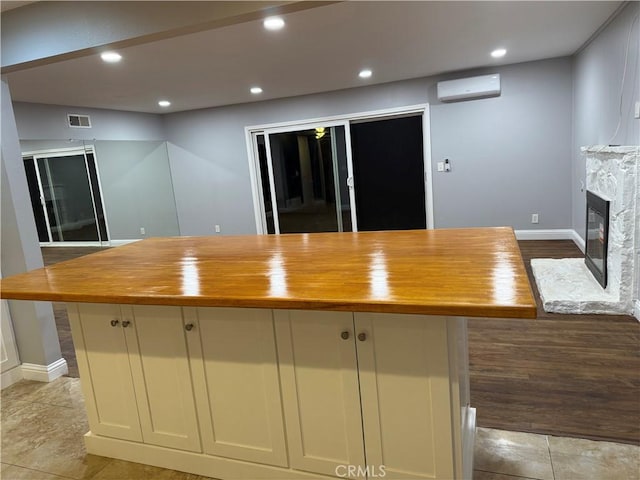 4561 Mimosa Dr, Yorba Linda, CA 92886 - kitchen with wooden counters, a wall unit AC, a glass covered fireplace, recessed lighting, and light tile patterned floors