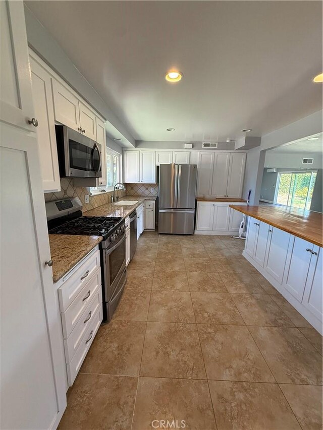 4561 Mimosa Dr, Yorba Linda, CA 92886 - kitchen with appliances with stainless steel finishes, white cabinetry, backsplash, wooden counters, and recessed lighting