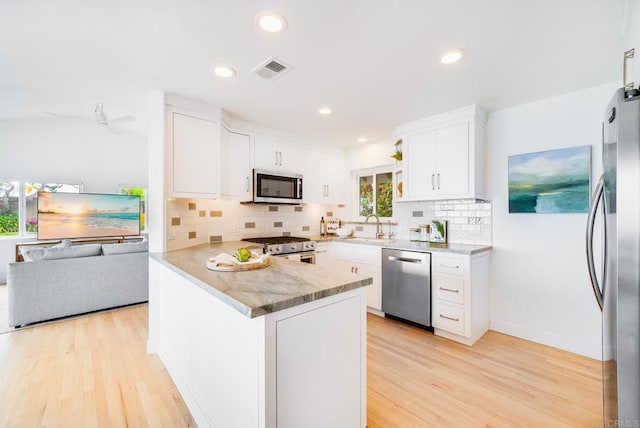 231 5th St, Encinitas, CA 92024 - kitchen with appliances with stainless steel finishes, light wood finished floors, a peninsula, white cabinetry, and decorative backsplash