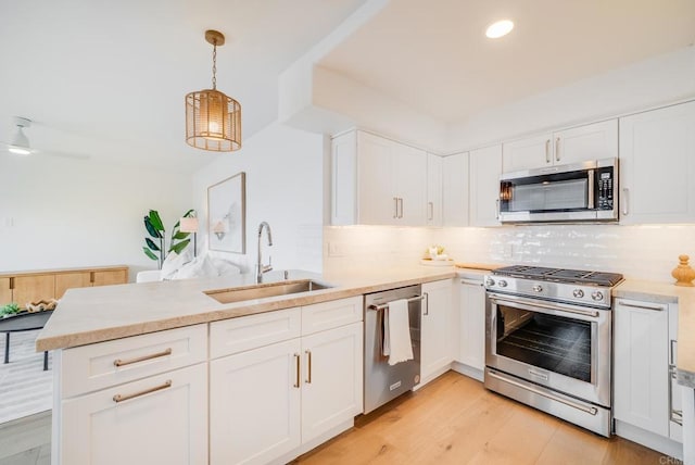 231 5th St, Encinitas, CA 92024 - kitchen featuring stainless steel appliances, a peninsula, light countertops, backsplash, and white cabinetry