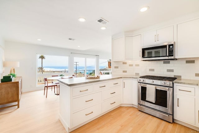 231 5th St, Encinitas, CA 92024 - kitchen with appliances with stainless steel finishes, a peninsula, light wood-style flooring, decorative backsplash, and recessed lighting