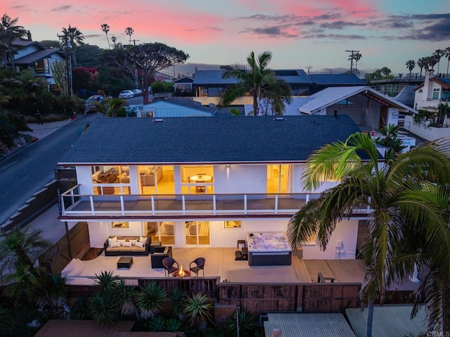 231 5th St, Encinitas, CA 92024 - back of house at dusk featuring an outdoor hangout area, a balcony, a patio area, roof with shingles, and stucco siding