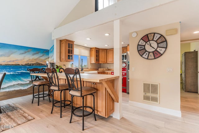 4534 La Brea St, Oxnard, CA 93035 - kitchen featuring butcher block countertops, brown cabinetry, light wood-style flooring, a breakfast bar area, and stainless steel microwave