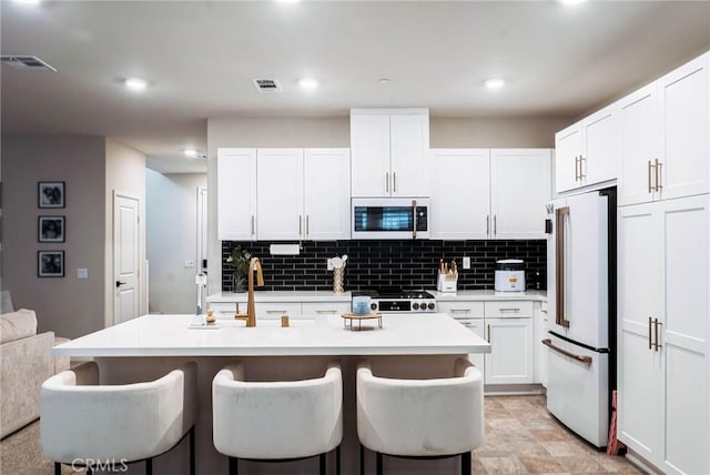4098 Summer Way, Corona, CA 92883 - kitchen featuring white appliances, a breakfast bar, decorative backsplash, white cabinetry, and recessed lighting