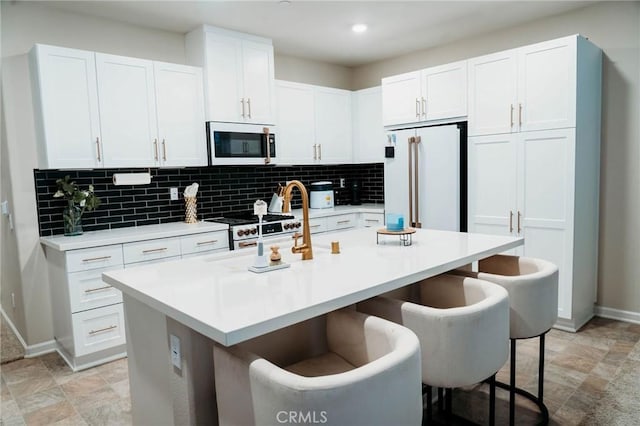 4098 Summer Way, Corona, CA 92883 - kitchen with premium appliances, a kitchen bar, white cabinetry, light countertops, and a kitchen island with sink