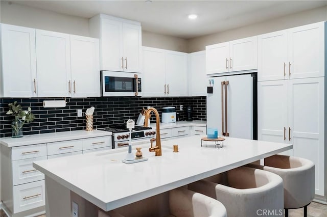 4098 Summer Way, Corona, CA 92883 - kitchen featuring premium appliances, a kitchen bar, light countertops, decorative backsplash, and white cabinetry