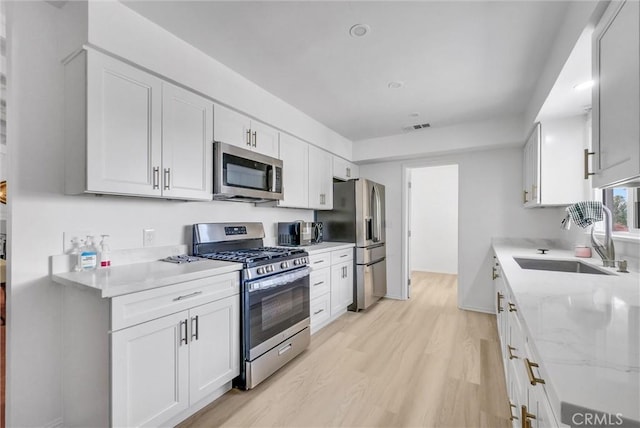 18295 Aguiro St, Rowland Heights, CA 91748 - kitchen with stainless steel appliances, white cabinetry, light stone counters, and light wood-type flooring
