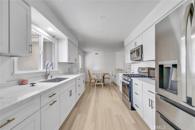 18295 Aguiro St, Rowland Heights, CA 91748 - kitchen featuring appliances with stainless steel finishes, white cabinetry, light wood-style floors, and light stone countertops