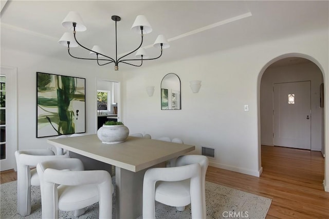 2982 Edgewick Rd, Glendale, CA 91206 - dining space with arched walkways, a chandelier, and light wood-style flooring