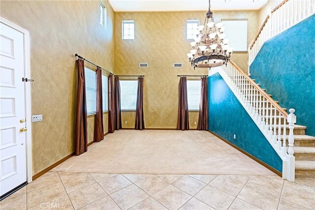 14145 Prairie Creek Pl, Eastvale, CA 92880 - carpeted foyer featuring stairway, a chandelier, tile patterned flooring, and a towering ceiling